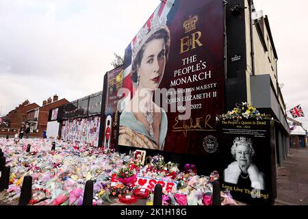 Dopo la scomparsa del Monarca britannico, la gente depone fiori in un murale raffigurante la Regina Elisabetta II sulla Shankill Road a Belfast. Foto Stock