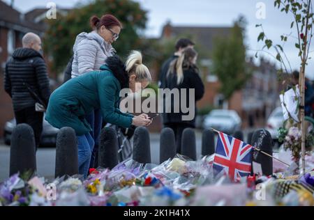 I membri del pubblico visitano un murale alla Regina Elisabetta II sulla Shankill Road a Belfast, davanti al minuto di silenzio nazionale in memoria della Regina Elisabetta II Il paese osserva un minuto di silenzio per ricordare la Regina, con persone invitate a celebrare l'occasione privatamente a casa, a casa o per strada, o in occasione di eventi e di veglie della comunità. Data immagine: Domenica 18 settembre 2022. Foto Stock