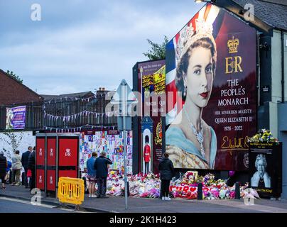 I membri del pubblico visitano un murale alla Regina Elisabetta II sulla Shankill Road a Belfast, davanti al minuto di silenzio nazionale in memoria della Regina Elisabetta II Il paese osserva un minuto di silenzio per ricordare la Regina, con persone invitate a celebrare l'occasione privatamente a casa, a casa o per strada, o in occasione di eventi e di veglie della comunità. Data immagine: Domenica 18 settembre 2022. Foto Stock