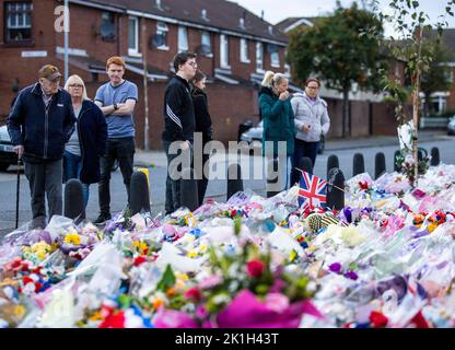 I membri del pubblico visitano un murale alla Regina Elisabetta II sulla Shankill Road a Belfast, davanti al minuto di silenzio nazionale in memoria della Regina Elisabetta II Il paese osserva un minuto di silenzio per ricordare la Regina, con persone invitate a celebrare l'occasione privatamente a casa, a casa o per strada, o in occasione di eventi e di veglie della comunità. Data immagine: Domenica 18 settembre 2022. Foto Stock