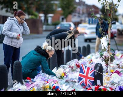 I membri del pubblico visitano un murale alla Regina Elisabetta II sulla Shankill Road a Belfast, davanti al minuto di silenzio nazionale in memoria della Regina Elisabetta II Il paese osserva un minuto di silenzio per ricordare la Regina, con persone invitate a celebrare l'occasione privatamente a casa, a casa o per strada, o in occasione di eventi e di veglie della comunità. Data immagine: Domenica 18 settembre 2022. Foto Stock