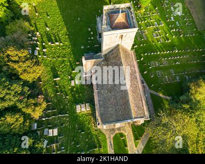 Una vista aerea della chiesa di Santa Maria la Vergine e il cimitero alla luce del sole serale, nel villaggio di Shipley, Sussex occidentale, Inghilterra, Regno Unito Foto Stock