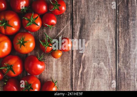 Pomodori su sfondo di legno, cornice di frutta di pomodoro rosso appena raccolta, fondo di cottura, spazio copia Foto Stock