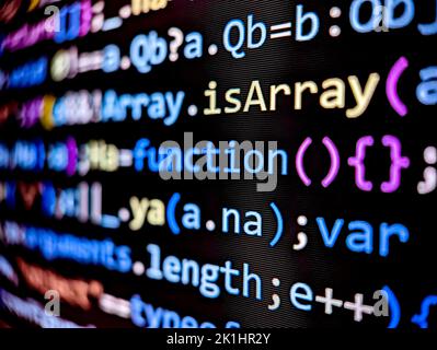 Primo piano del codice software sullo schermo di un computer con lettere e numeri colorati visualizzati in modalità scura su sfondo nero Foto Stock