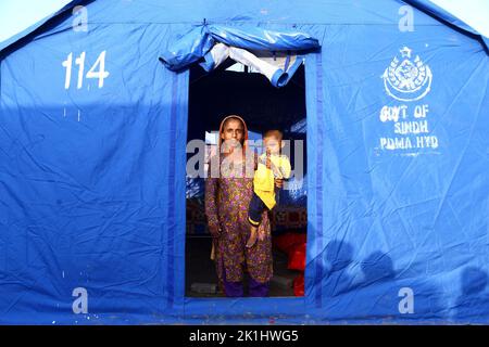 Hyderabad, Pakistan. 18th Set, 2022. Una donna affetta da alluvioni con il suo bambino è vista in una tenda di fortuna alla periferia di Hyderabad, Pakistan, 18 settembre 2022. Il numero totale di morti in Pakistan a causa delle piogge monsoniche e delle inondazioni di questa stagione da metà giugno è salito a circa 1.545, insieme a 12.860 feriti, ha affermato la National Disaster Management Authority (NDMA). Credit: Str/Xinhua/Alamy Live News Foto Stock