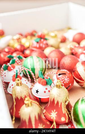 Scatola di ornamenti misti di alberi di Natale, palline e campane nei classici colori tradizionali di rosso, verde, bianco e oro. Foto Stock