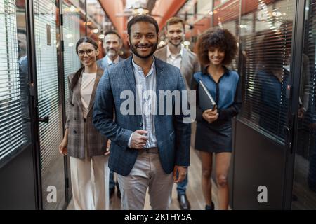Gruppo di uomini d'affari felici e motivati che si riuniscono in ufficio con il loro leader Foto Stock