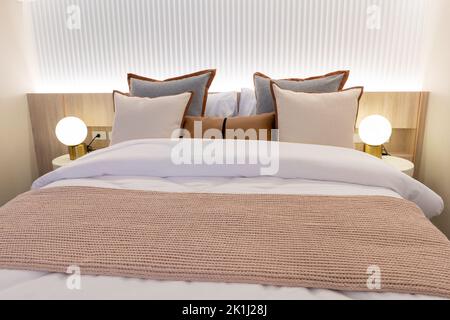 decorazioni con cuscini bianchi sul letto negli interni della camera da letto. Interno della camera da letto con lampade Foto Stock