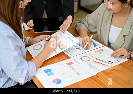 Gruppo di consulenti finanziari o contabili asiatici millennial professionisti che lavorano, brainstorming e analizzano insieme i rapporti sulle vendite finanziarie. tè Foto Stock