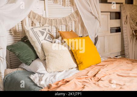 Design moderno degli interni. Letto con baldacchino e cuscini di colore arancione, coperta.interno camera da letto, in stile scandinavo.accogliente camera in appartamento con Foto Stock