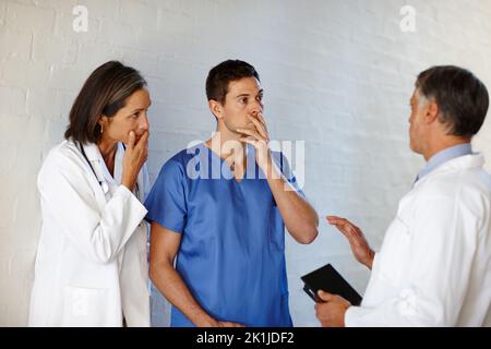 La sua condizione è diventata critica... Un colpo corto di tre medici in piedi e avendo una conversazione seria. Foto Stock