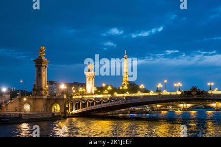 Parigi, Francia - 19 aprile 2022: Torre Eiffel illuminata e Pont Alexandre III, visto dal fiume Senna di notte Foto Stock
