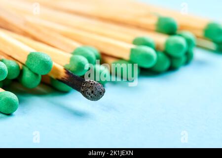 Primo piano di un gruppo di partite con teste verdi e una partita bruciata su sfondo blu Foto Stock