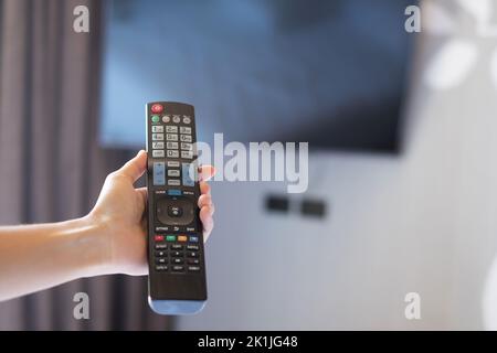 Utilizzare il telecomando per regolare lo Smart TV all'interno della camera moderna a casa o in un hotel di lusso Foto Stock