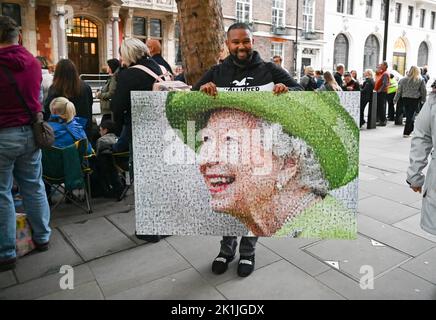 Londra UK 19th settembre 2022 - Un uomo porta un grande ritratto della Regina mentre le folle si riuniscono vicino a Parliament Square a Londra per vedere i funerali della Regina Elisabetta II : Credit Simon Dack / Alamy Live News Foto Stock