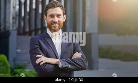 Riuscito uomo d'affari sorridente sicuro in piedi outdoor del vestito dell'ufficio della costruzione del background bello lavoratore professionale del capo maschio positivo Foto Stock