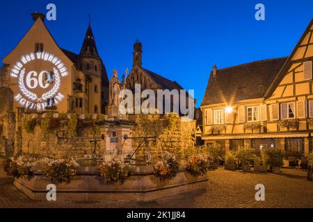 Una serata estiva sulla piazza principale (con la fontana di Saint-Léon) nel villaggio di Eguisheim in Alsazia francese. L'edizione 60th del viticoltore Foto Stock