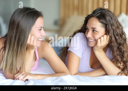 Due donne felici che si guardano sdraiate su un letto nella camera da letto Foto Stock