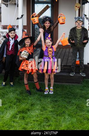 Allegri bambini interracial che celebrano Halloween durante la festa nel cortile Foto Stock