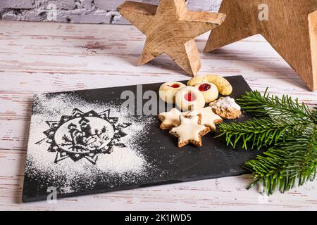 Biscotti di Natale decorati su un piatto di ardesia con un motivo di farina Foto Stock