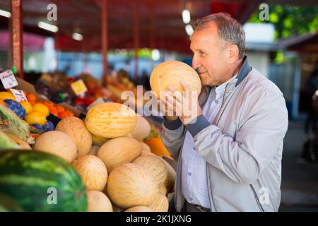 Uomo scelta melone fresco sul mercato Foto Stock