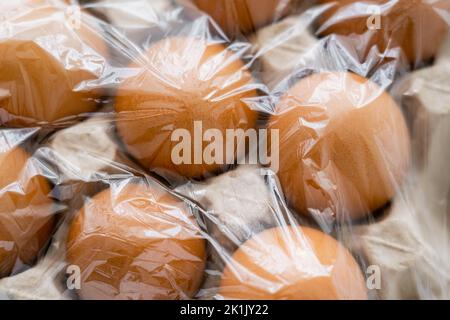 Vista dall'alto di uova marroni in contenitore di cartone con cellofan Foto Stock