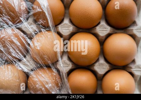 Vista dall'alto di cellophane su uova di pollo marrone nel contenitore Foto Stock