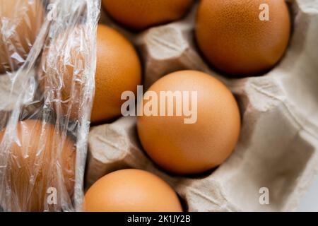 Vista ravvicinata delle uova di pollo in un vassoio sfocato con cellophane Foto Stock