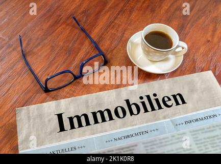 Quotidiano immobiliare con bicchieri e caffè su una scrivania Foto Stock