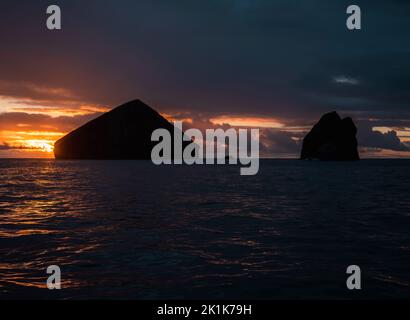 Tramonto sull'Oceano Atlantico dalle isole Azzorre portoghesi. Una linea costiera increspata durante il tramonto caratterizzata da affioramenti rocciosi e un tramonto incredibile. Foto Stock