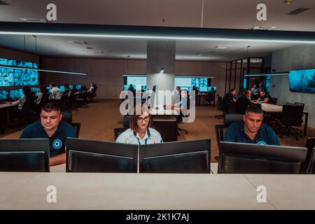 Gruppo di operatori del data center di sicurezza che lavorano in una sala di monitoraggio TVCC alla ricerca di più monitor funzionari che monitorano più schermi per Foto Stock