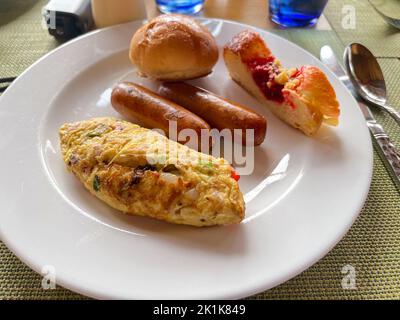 Un piatto salutare per la colazione con omelette alle uova, salsicce e pane servito su un piatto bianco. Foto Stock