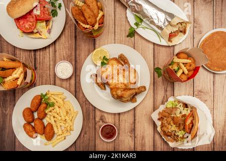 Piatti fast food, con pollo alla griglia, hamburger, strisce di pollo, crocchette e sandwich kebab Foto Stock