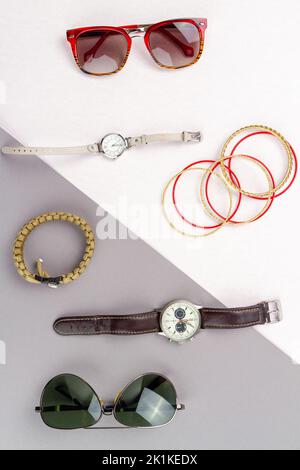 Piatto contrasto di posa di accessori uomo e donna. Occhiali da vista dall'alto con orologio e braccialetti. Foto Stock