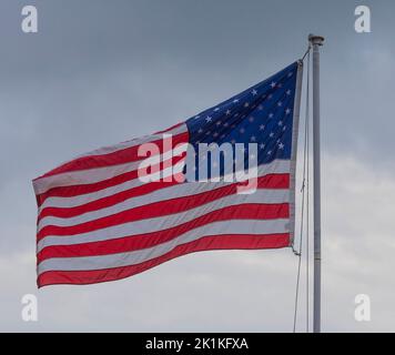 Bandiera americana fiero di volare con sottili nuvole dietro Foto Stock