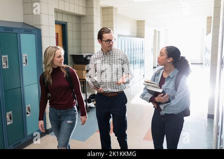 Insegnante di scuola superiore e studenti che parlano e camminano in corridoio
