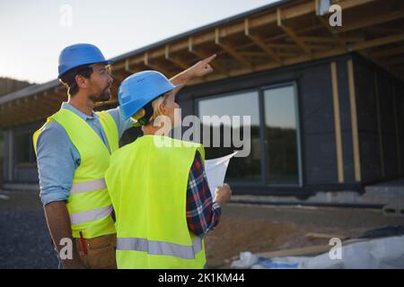 Ingegneri edili o architetti con Blueprints controllo eco cantiere di legno telaio casa Foto Stock