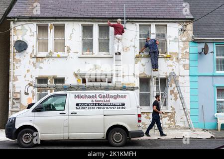 Pittori locali e decoratori al lavoro su una casa in Ardara, Contea di Donegal, Irlanda Foto Stock