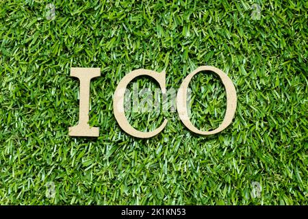 Lettera dell'alfabeto di legno in parola ICO (abbreviazione dell'offerta iniziale della moneta o dell'offerta iniziale della valuta) su fondo verde dell'erba Foto Stock