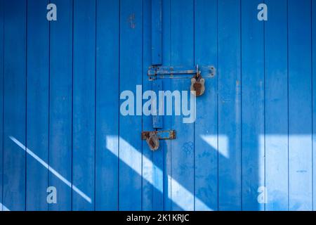 Porta in legno blu con due lucchetti Foto Stock