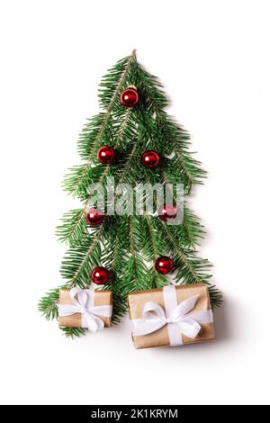 Albero di Natale decorato creato da ramoscelli di abete con palle rosse di natale e regali per il nuovo anno isolato su sfondo bianco. Scatole regalo con nastri bianchi sotto l'albero di Natale Foto Stock