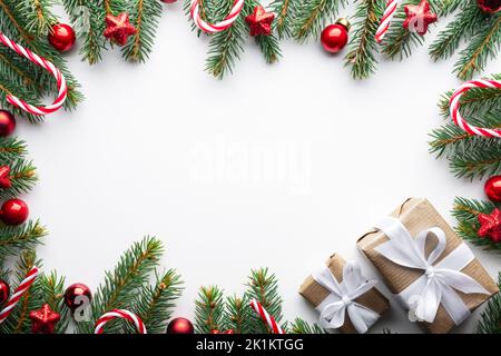 Sfondo di Natale creativo con palle di Natale, ramoscelli di pino e decorazioni stelle dorate su sfondo bianco. Disposizione piatta, vista dall'alto, spazio di copia Foto Stock