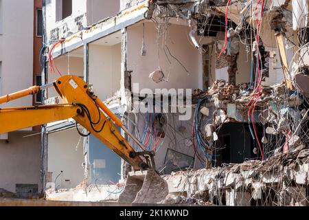 Una pesante macchina da lavoro industriale, scavatore sta distruggendo un vecchio edificio abbandonato . Foto di alta qualità Foto Stock