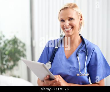 La tecnologia rende il mio lavoro molto più facile. Un ritratto di un bel giovane medico che tiene una tavoletta. Foto Stock