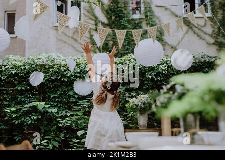 Vista posteriore del bambino felice che gioca con le decorazioni di nozze. Foto Stock