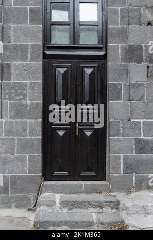 Vecchia casa in pietra classica con rustico, nero, intagliato, porta in legno d'epoca. Texture delle porte e sfondo. Foto di alta qualità Foto Stock