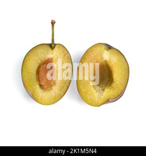 prugne fresche tagliate mature isolate su fondo bianco, frutta spezzata a metà con osso, vista dall'alto Foto Stock