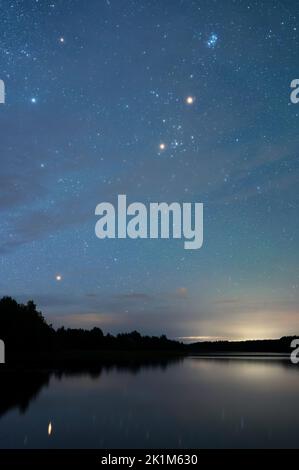 Paesaggio notturno autunnale sotto il cielo stellato. Stelle che si riflettono da una superficie d'acqua calma. Foto Stock
