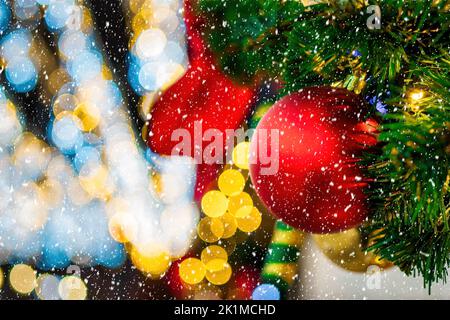 Palle di Natale, giocattoli e ghirlande incandescenti su un abete artificiale con neve caduta. Sfondo astratto di xmas. Foto Stock