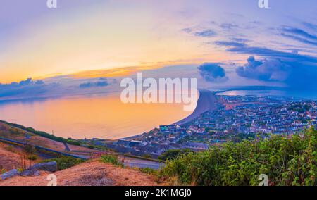 Splendida vista al tramonto sulla spiaggia di chesil sull'isola di Portland, sulla costa giurassica del Dorset, guardando indietro verso Weymouth Foto Stock